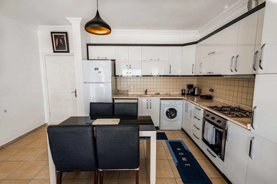 Bright modern kitchen with white cabinets, dining area, and appliances.